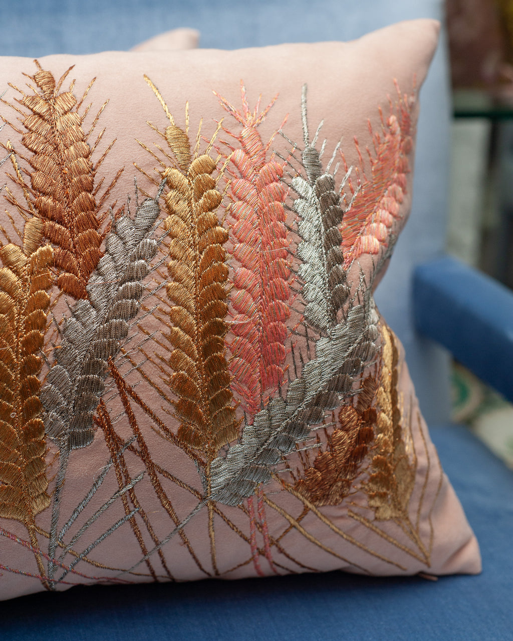 A CONTEMPORARY EMBROIDERED PILLOW ON SOFT PINK ULTRASUEDE WITH METALLIC WHEAT