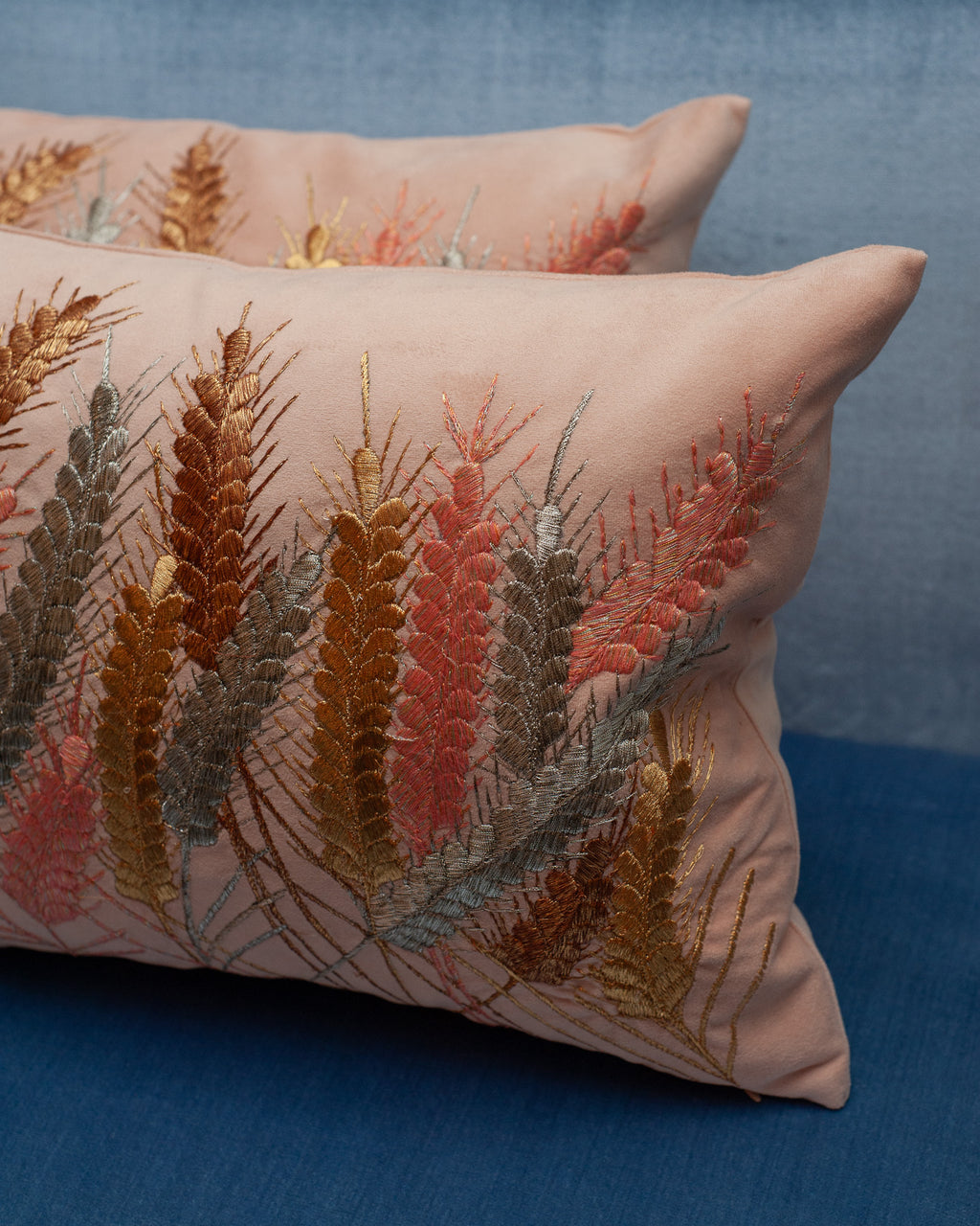 A CONTEMPORARY EMBROIDERED PILLOW ON SOFT PINK ULTRASUEDE WITH METALLIC WHEAT