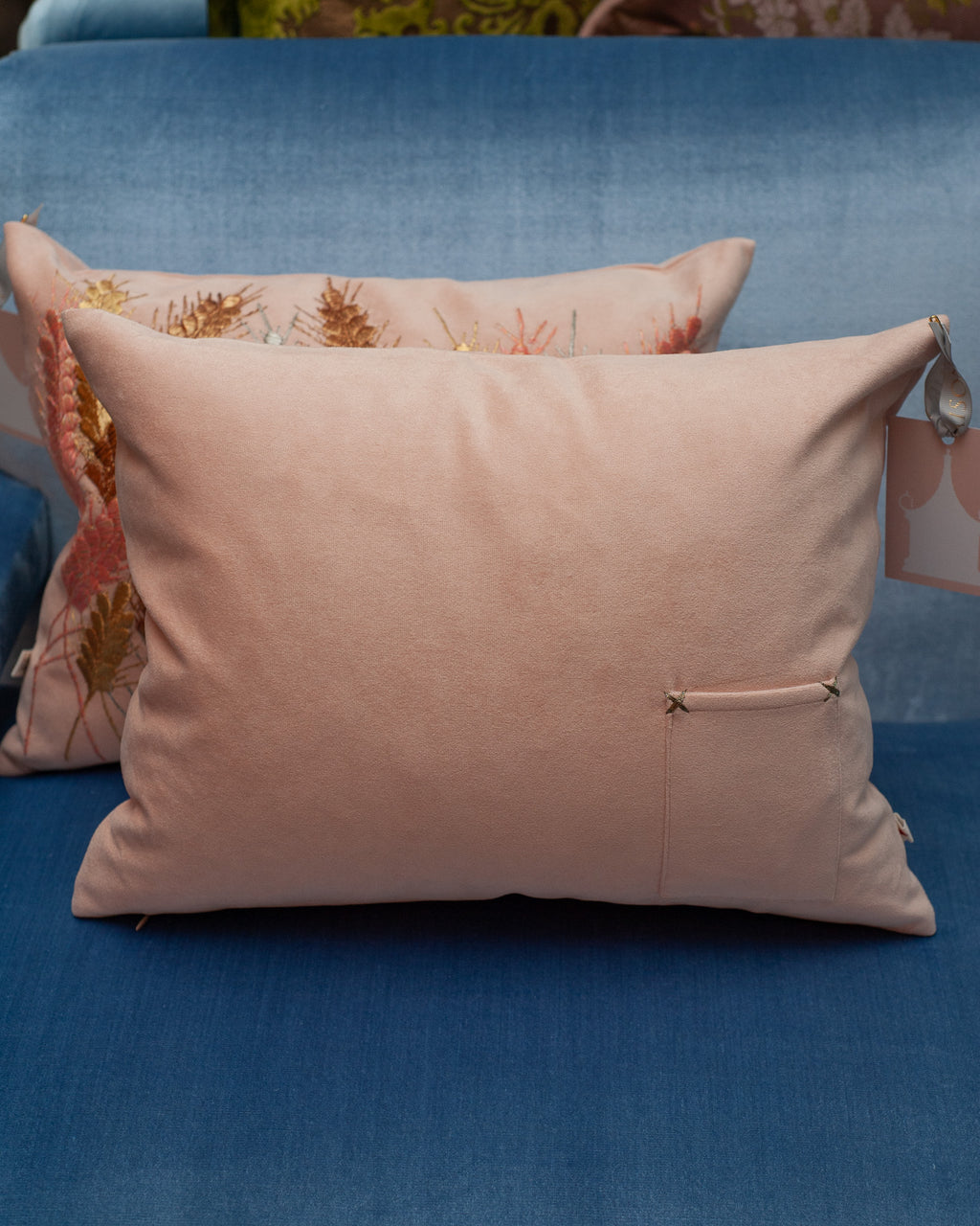 A CONTEMPORARY EMBROIDERED PILLOW ON SOFT PINK ULTRASUEDE WITH METALLIC WHEAT