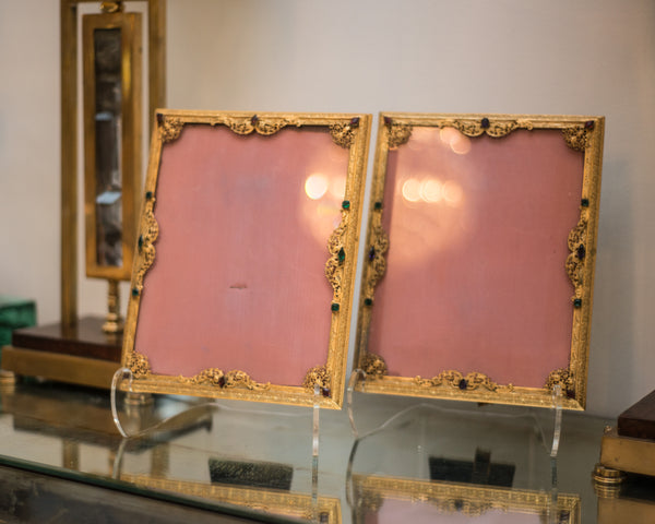 An antique gold picture frame with filigree work and jewels backed in pink silk moiré.