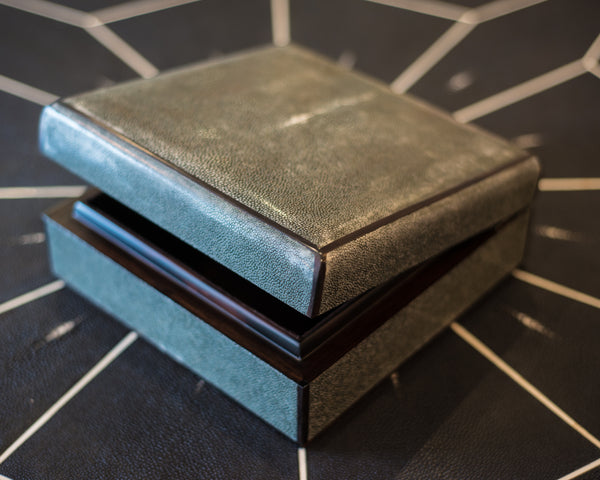 A square grey Shagreen decorative box finished with exotic wood and a felt interior. Maison Nurita’s Shagreen boxes are more than just decorative, they can be a special place to hold your coveted jewelry, love letters or sentimental photos. Hand crafted, custom dyed and beautifully finished, these exotic boxes make a perfect gift.